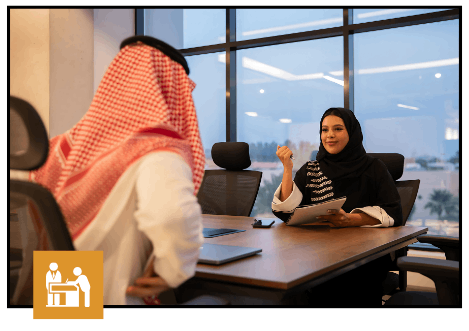 Businesswoman in hijab discussing VAT with man in traditional attire in a modern office.